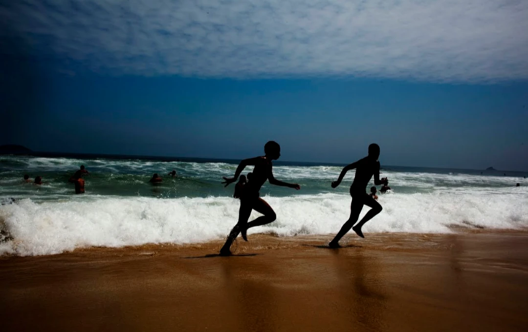 Duas crianças correndo junto às ondas