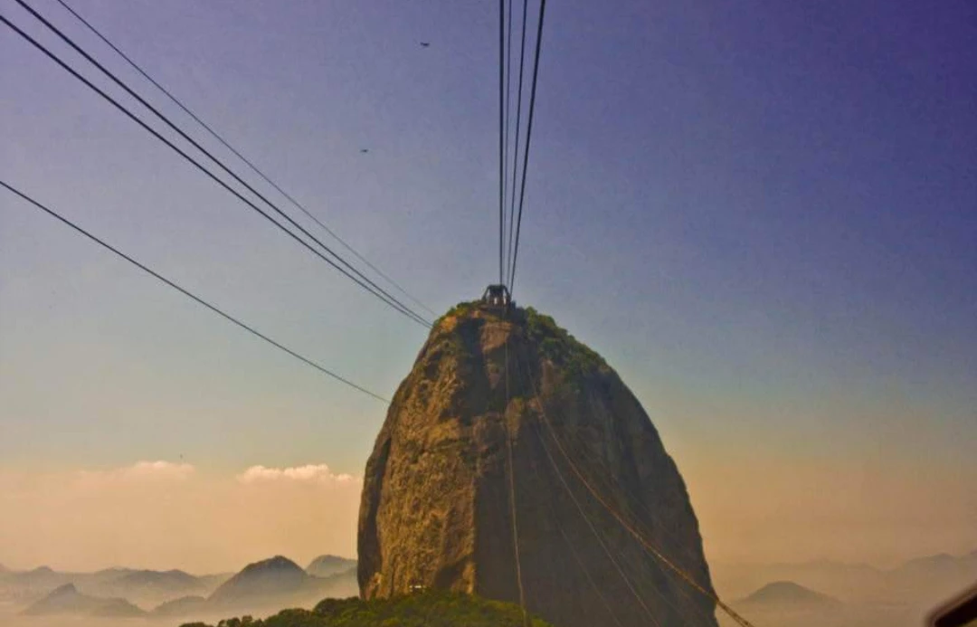 Cabos de um bondinho diante de uma montanha ao entardecer
