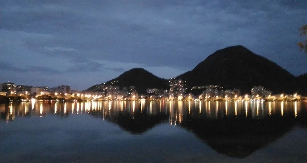 Cidade e montanhas refletidas na água à noite