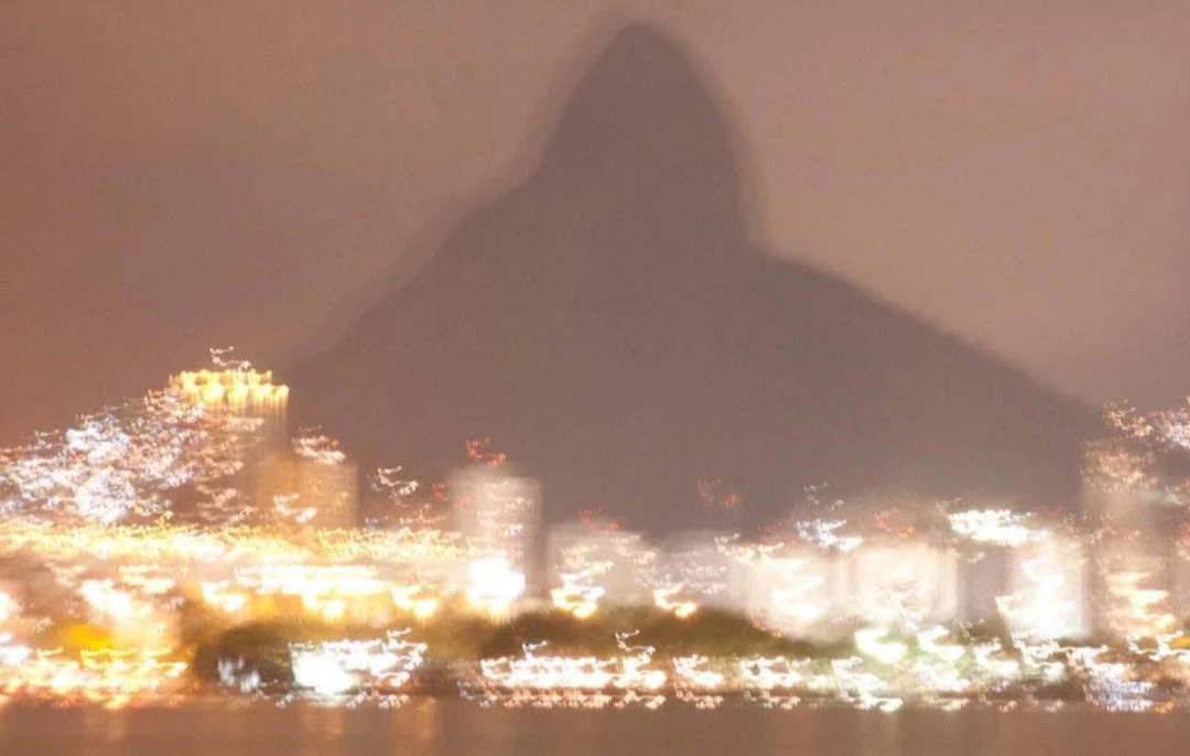 Montanha em silhueta sobre as luzes da cidade à noite