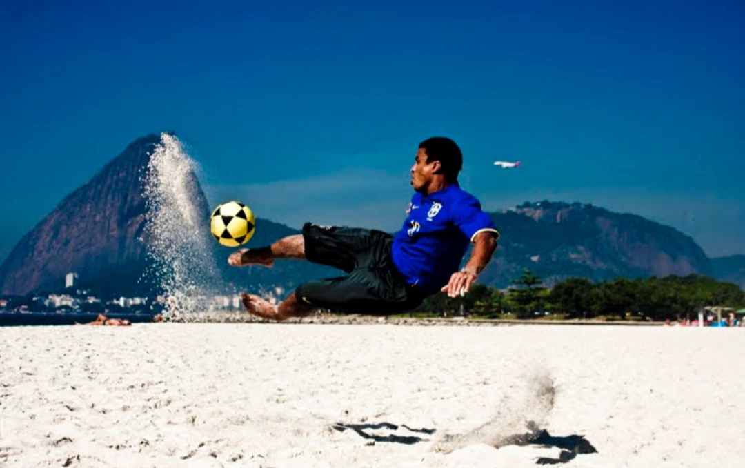 Pessoa com bola na praia diante de uma montanha