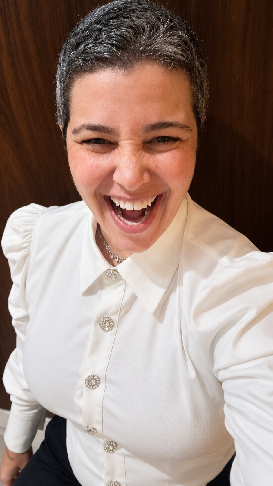 Retrato de Carol Beiriz sorrindo, com camisa branca